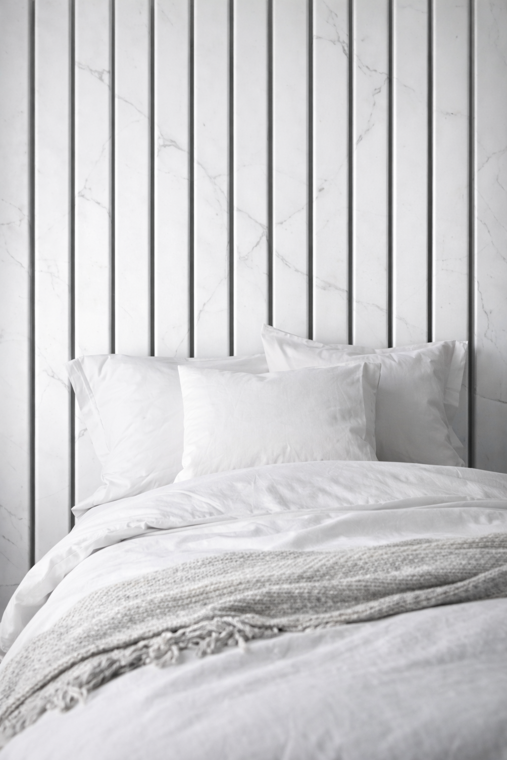 White bedding set on a bed with marble slat panels.